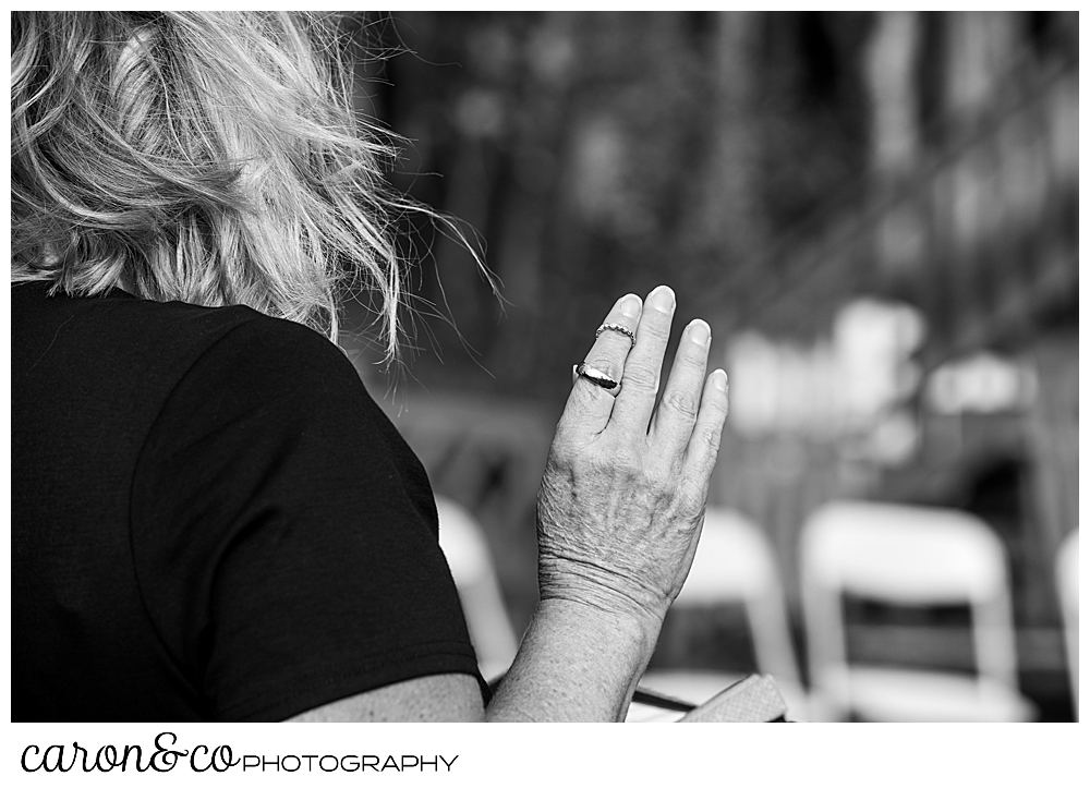 a black and white photo with a wedding officiant wearing the wedding bands on her upheld hand