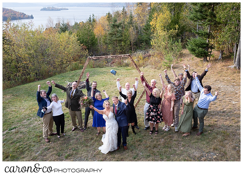 a bride and groom with their guests all cheering during a Rangeley Maine wedding