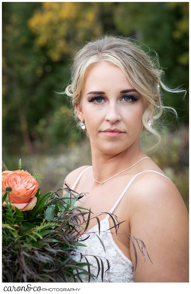 a beautiful bridal portrait of a blonde bride holding a bouquet with peach colored roses and greenery