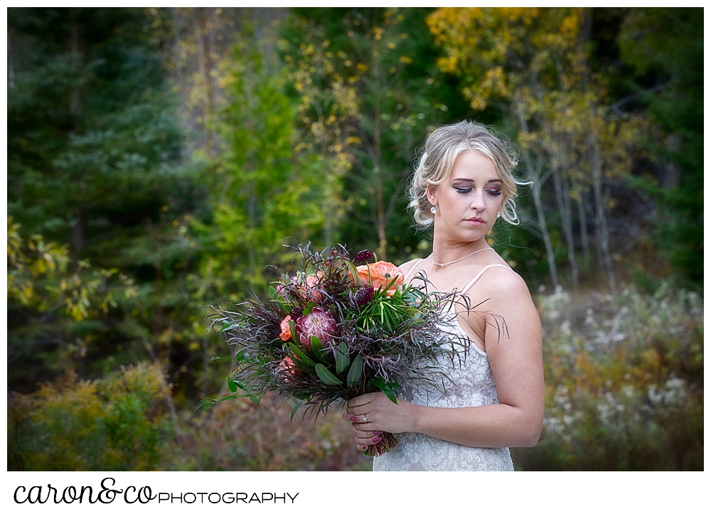 a bridal portrait of a bride her eyes closes, holding a bouquet with peach roses and greens