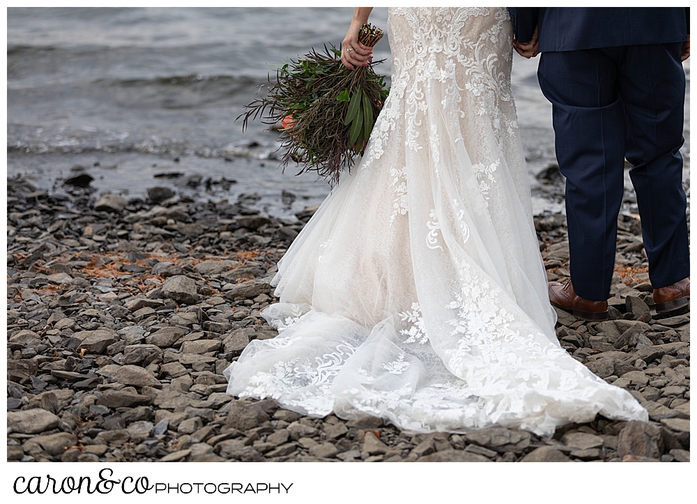 the back of a Martina Liana wedding dress, as a bride and groom stand with their backs to the camera, on the shores of Rangeley Lake, Rangeley Maine