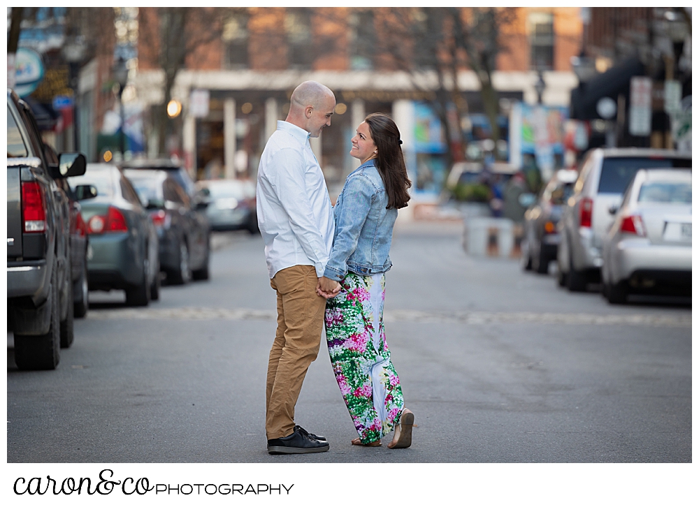 a man and woman in the middle of Exchange Street, Portland, Maine, during a Portland Maine spring engagement photo shoot