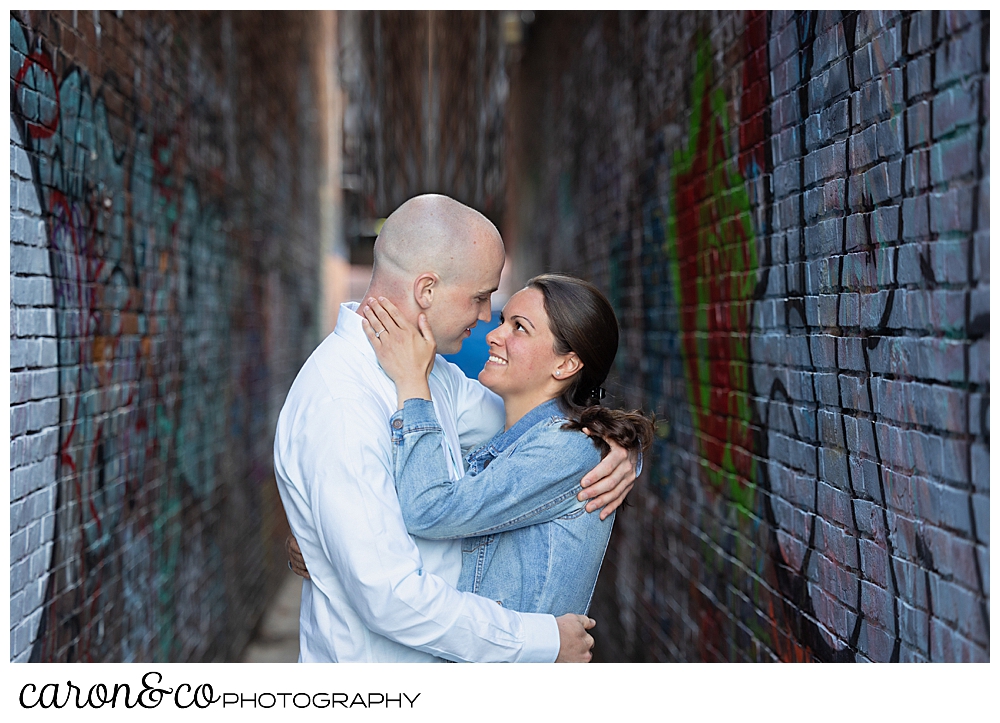 a man and woman hug in an alley way in the Old Port, Portland, Maine, during their Portland Maine engagement session