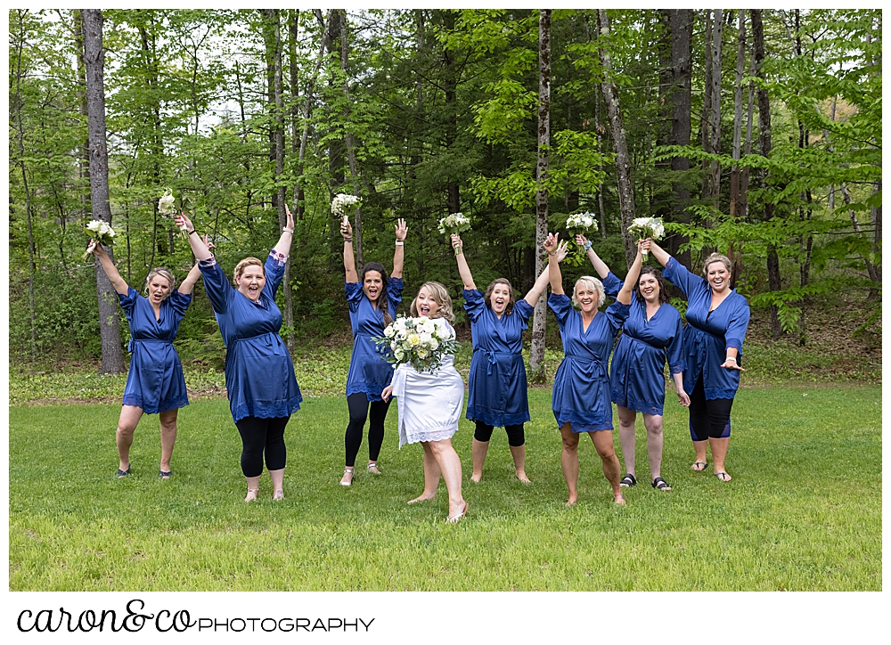 birde in a white robe, surrounded in bridesmaids in blue robes, cheering in a back yard