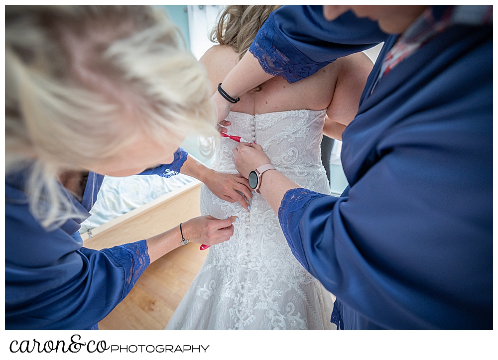 bridesmaids in blue, buttons up the back of a bride's wedding dress