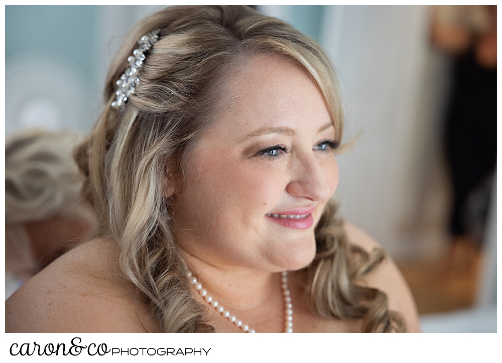 a bride smiles while her bridesmaids help her get ready for her wedding day