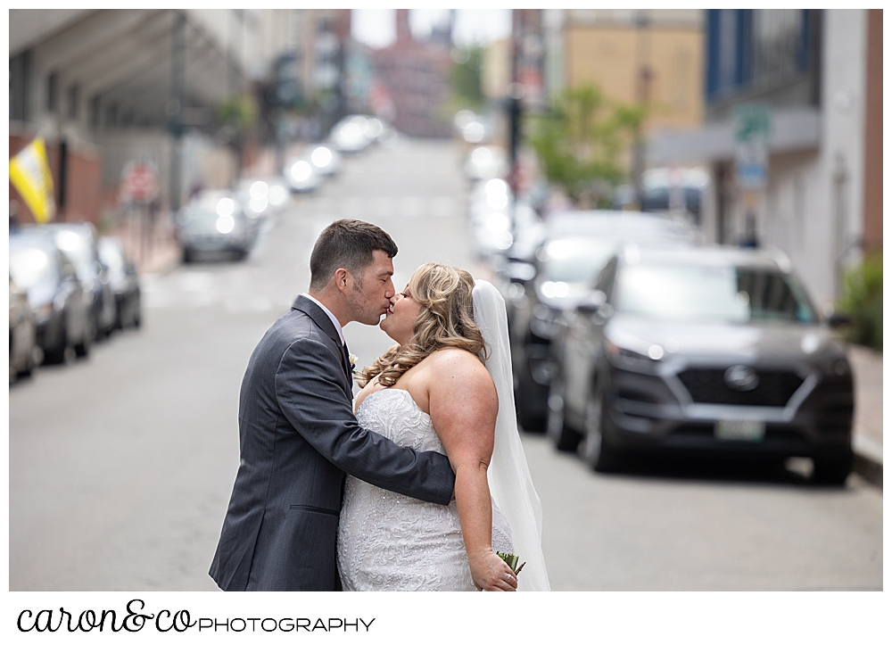 a bride and groom kiss in the middle of downtown Portland, Maine