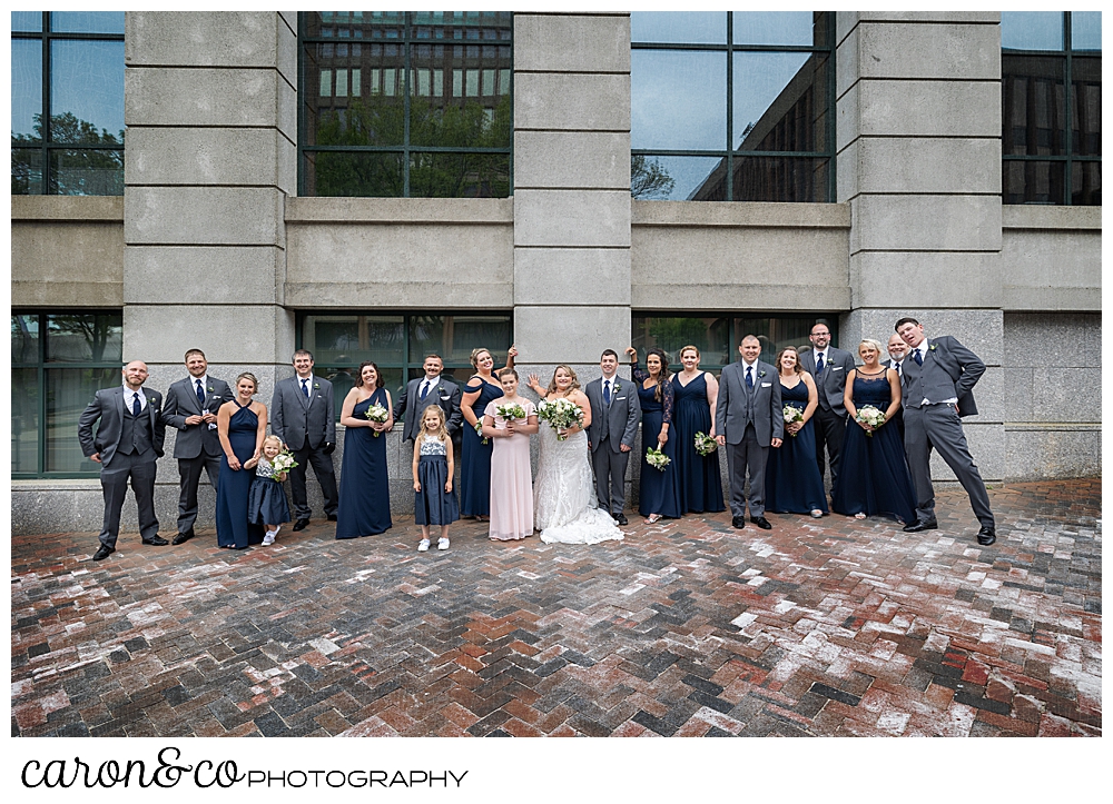 a bride and groom with their bridal party, pose in front of a building in the Old Port, Portland, Maine