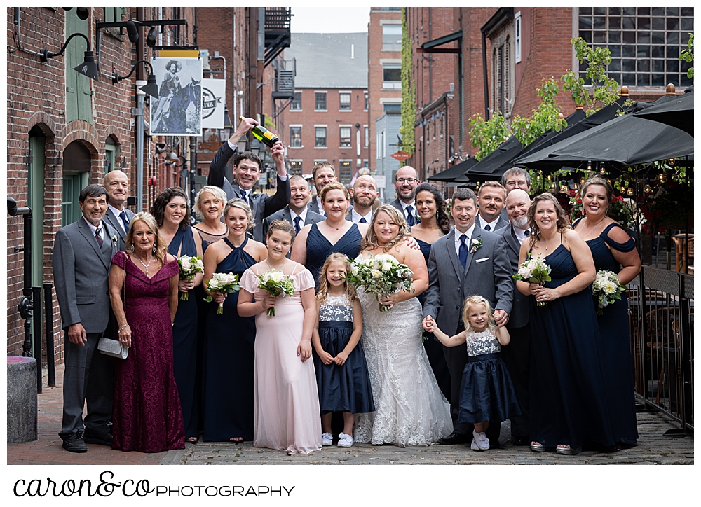 a bride and groom with their bridal party and parents, pose for a photo on the iconic Wharf Street, Portland, Maine