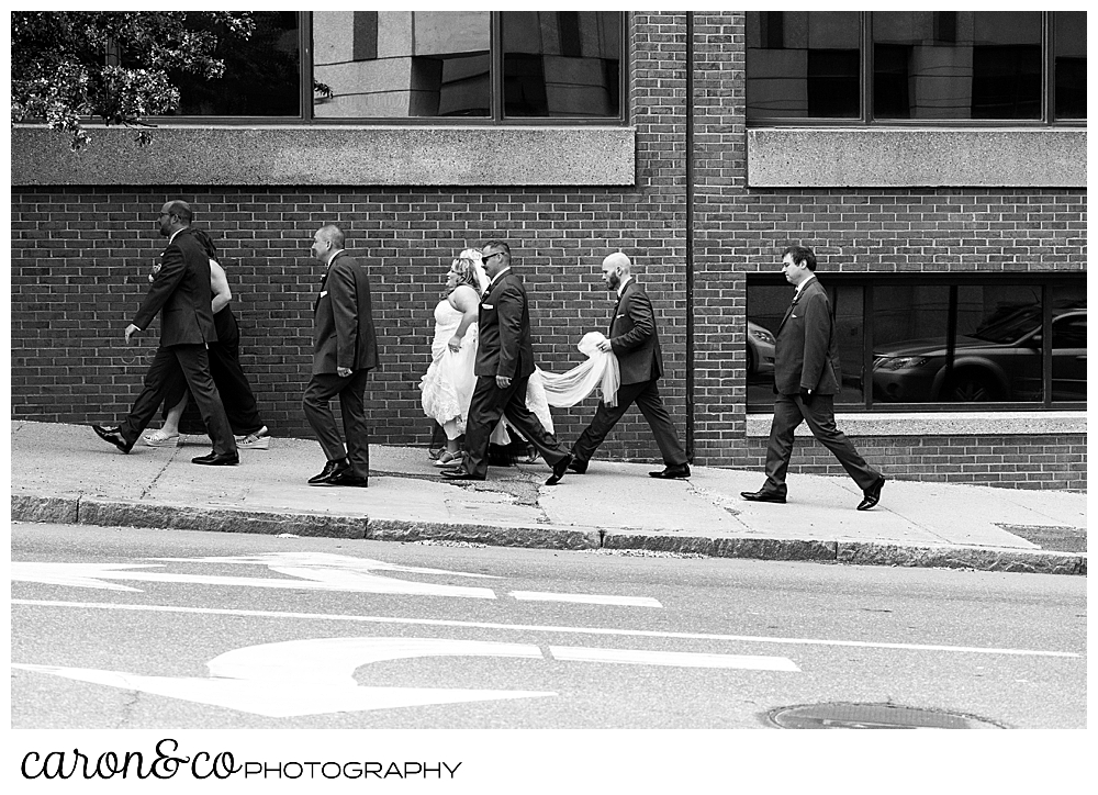 a black and white photo of a Bride and groom with their bridal party, walking along the sidewalk in Portland, Maine