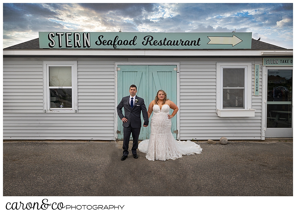 a bride and groom stand together in front of the Stern Seafood Restaurant, Pine Point, Scarborough, Maine