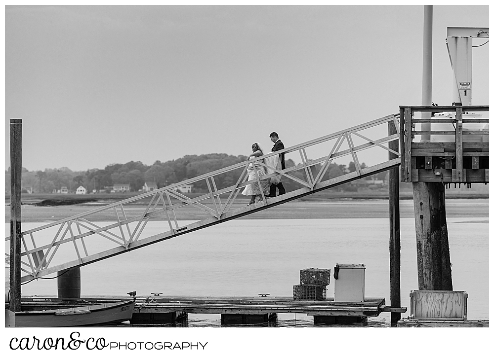 a black and white photo of a bride and groom walking down a ramp during a Pine Point Maine wedding