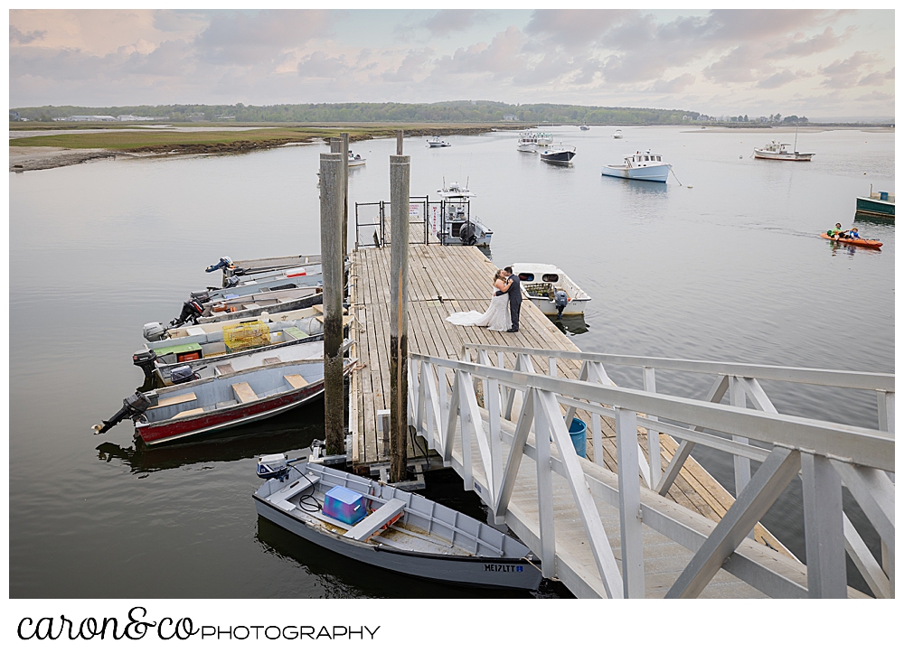 a bride and groom kiss on a dock at Pine Point Fisherman's Coop, during their Pine Point Maine wedding