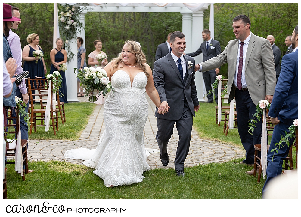 a bride and groom acknowledging their guests during their recessional at their Pine Point Maine wedding ceremony