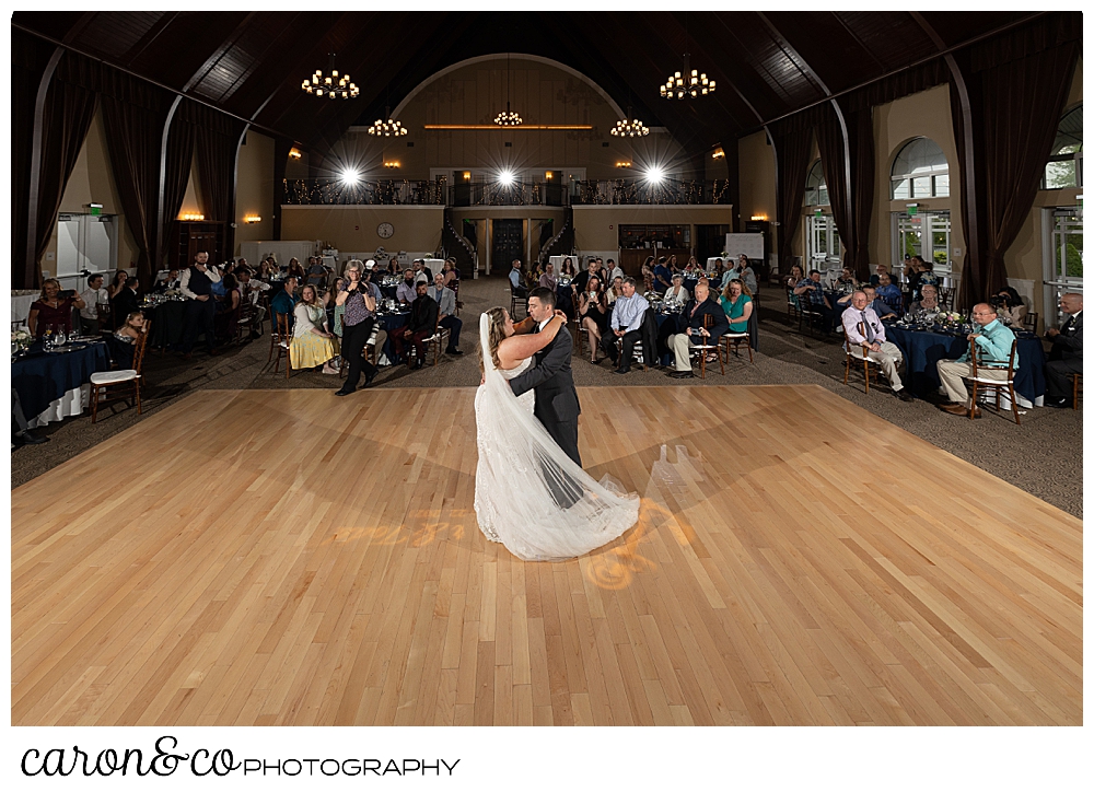 a bride and groom dance their first dance, as their families and guests look on at a Landing at Pine Point Maine wedding