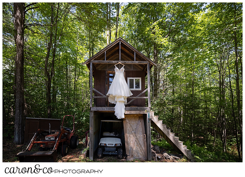 wedding dress hanging from a two story building, child's playhouse on top, storage on bottom,