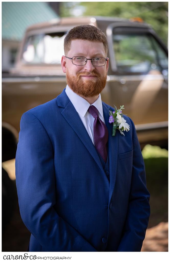 groom portrait, red haired groom wearing a blue suit, standing in front of his vintage pickup truck