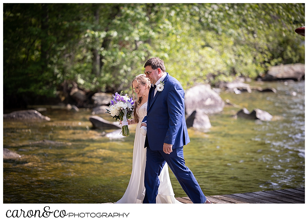 a bride and her dad are walking towards the aisle at a highland lake maine wedding ceremony