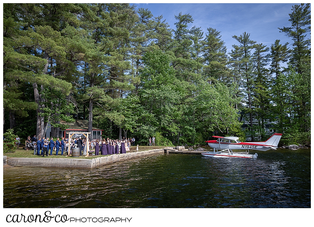 wide view of a Highland Lake Maine wedding ceremony, with a sea plane on the dock