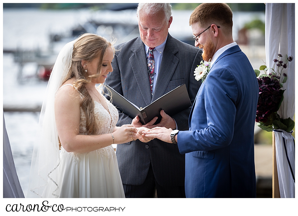 bride putting ring on groom's finger during their highland lake maine wedding ceremony