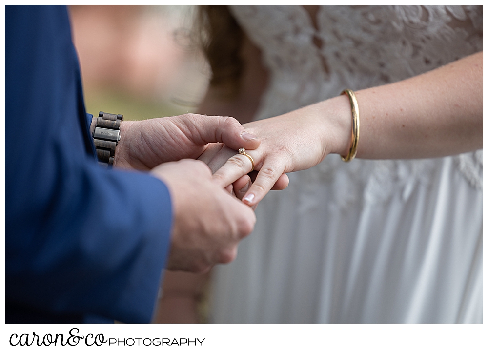 groom putting ring on bride's finger during their highland lake maine wedding ceremony