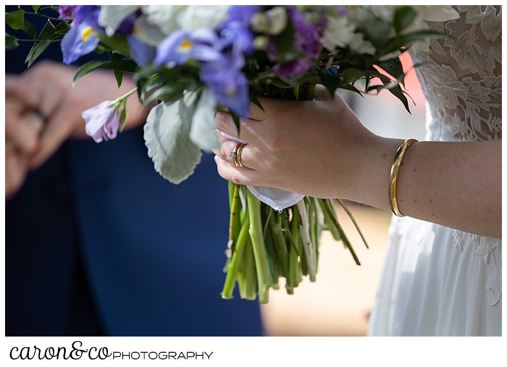 bride's hand with her new wedding band, holding a bouquet of purple, blue, white, and green flowers, at a highland lake maine wedding