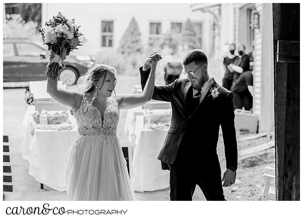 black and white photo of a bride and groom entering their reception