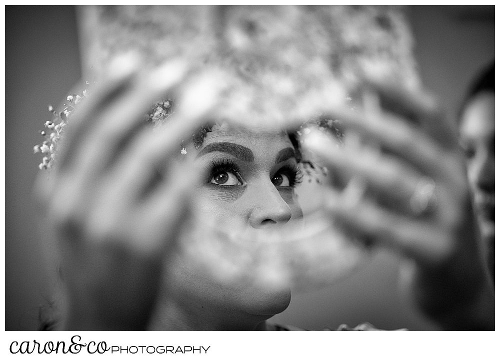 black and white photo of a bride holding a mirror, her eyes are peeking through the handle of the mirror