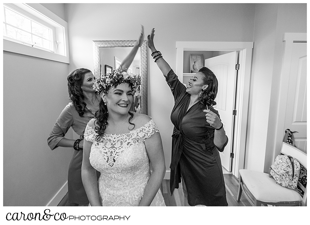 black and white photo of bridesmaids giving each other a high five behind a bride who's laughing