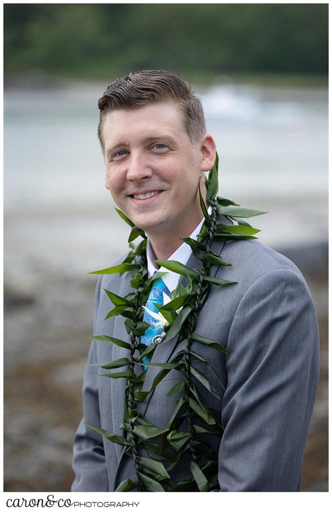 groom portrait of a groom wearing a gray suit, a blue tie, and a green lei