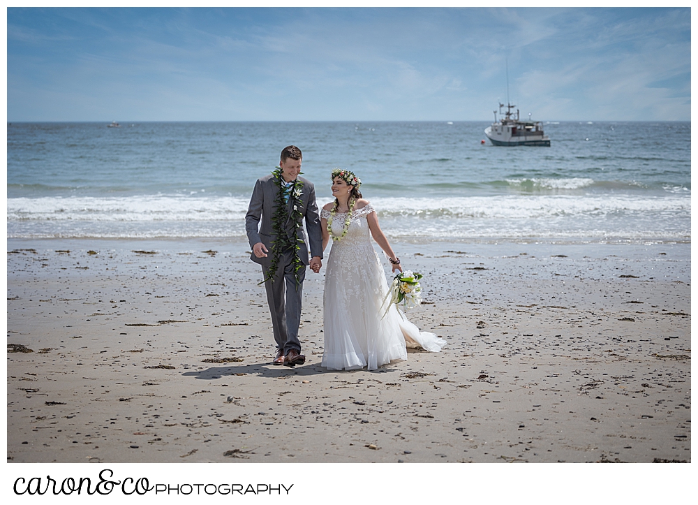 a bride and groom walk towards the camera on Colony Beach, Kennebunkport, Maine