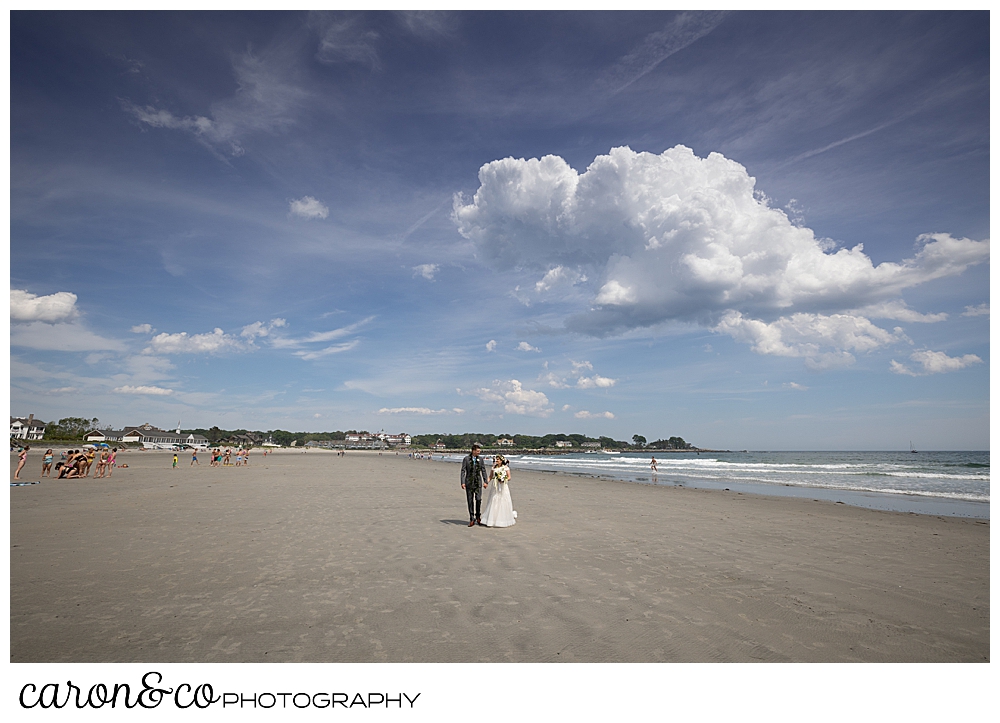 a bride and groom walk along Gooch's Beach in Kennebunk, Maiane