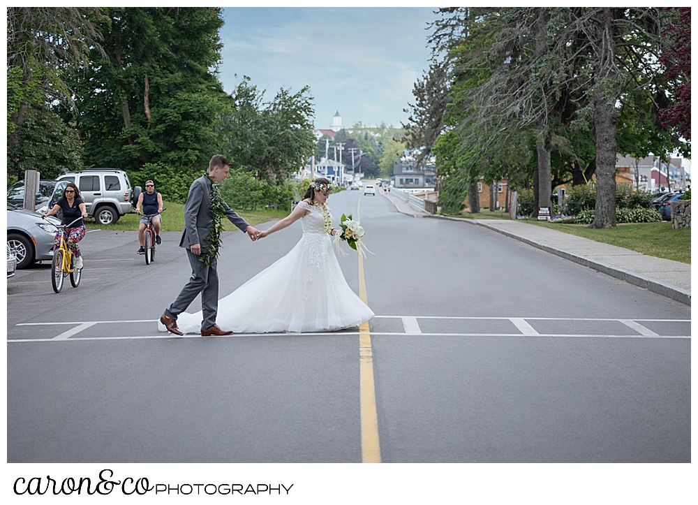 a bride and groom holding hands, cross the street on Ocean Avenue, Kennebunkport, Maine