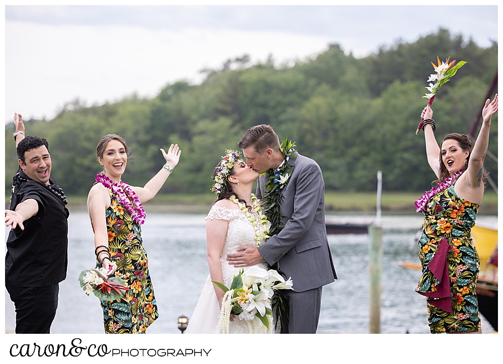 a bride and groom kiss, white their bridal party cheers next to them, at their Nonantum Resort tented wedding