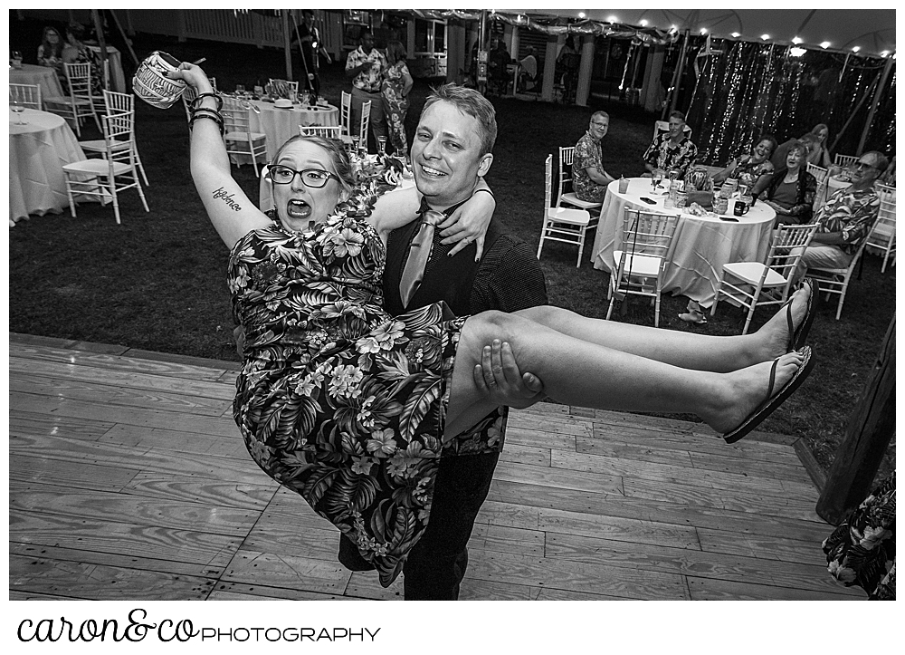 black and white photo of a man holding a woman and spinning her around, during a wedding reception