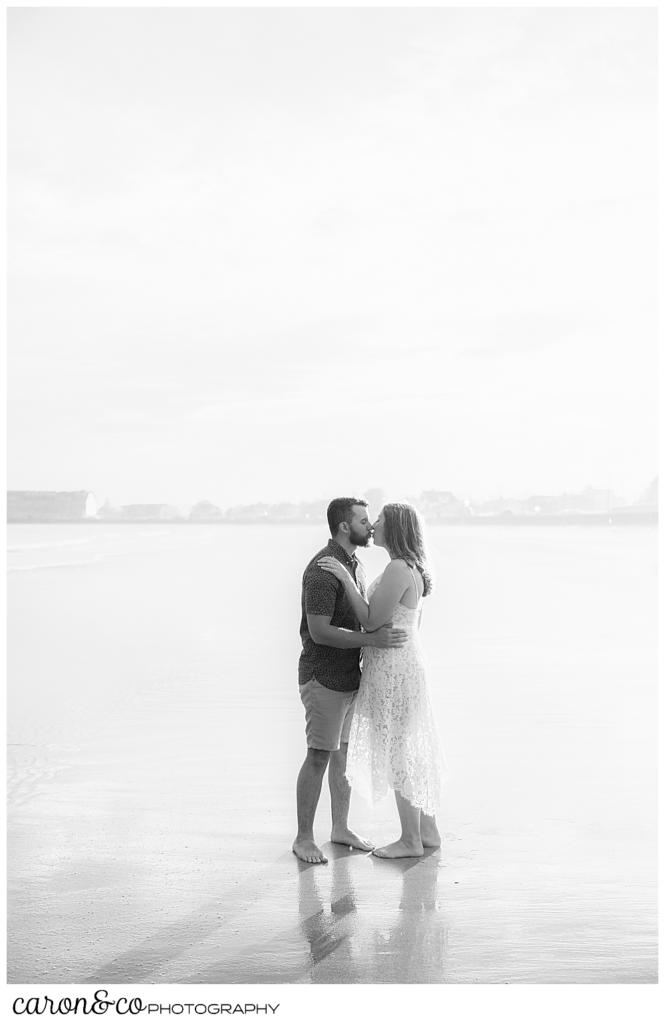 a black and white photo of a man and woman kissing on Gooch's Beach, Kennebunk, Maine