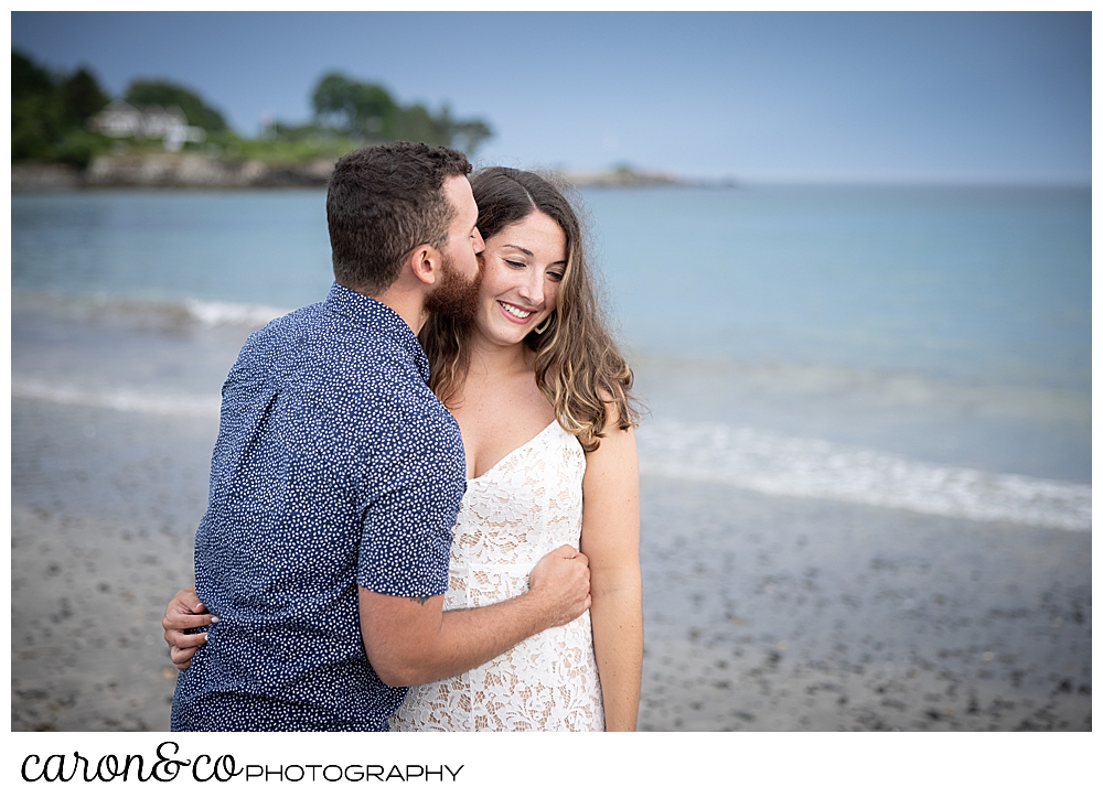 a man kisses a woman on the forehead at Colony Beach, during their Kennebunkport engagement session