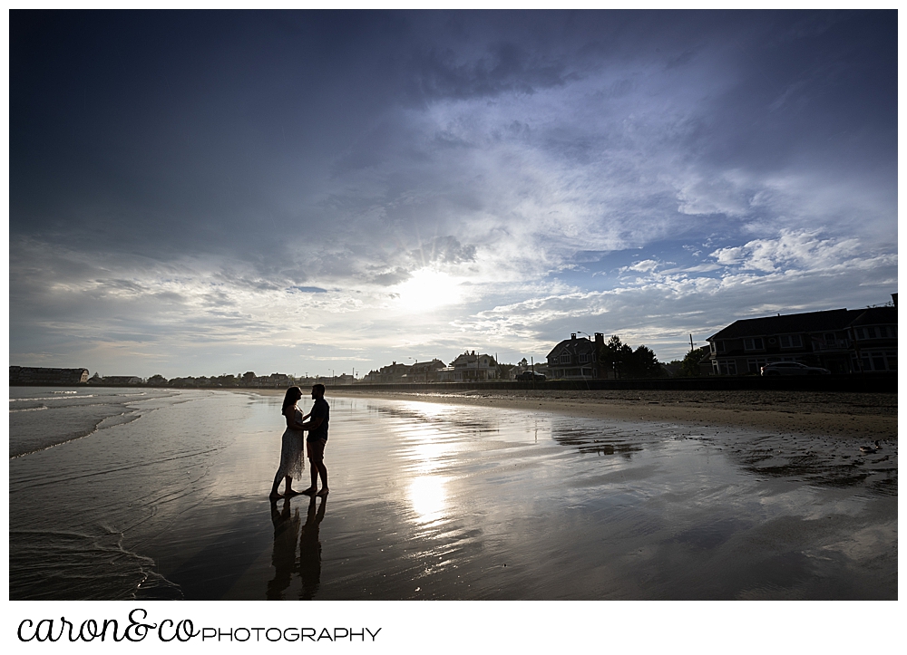 a man and woman stand together at Gooch's Beach in Kennebunk, Maine, during a Kennebunkport engagement session