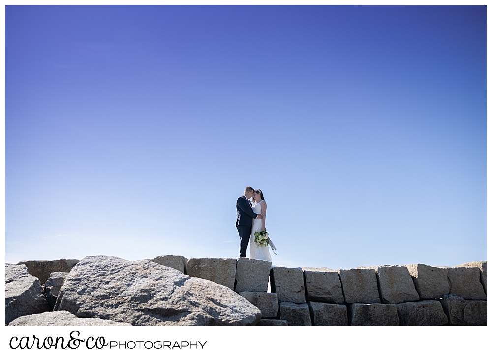 a bride and groom stand facing each other, their foreheads are touching