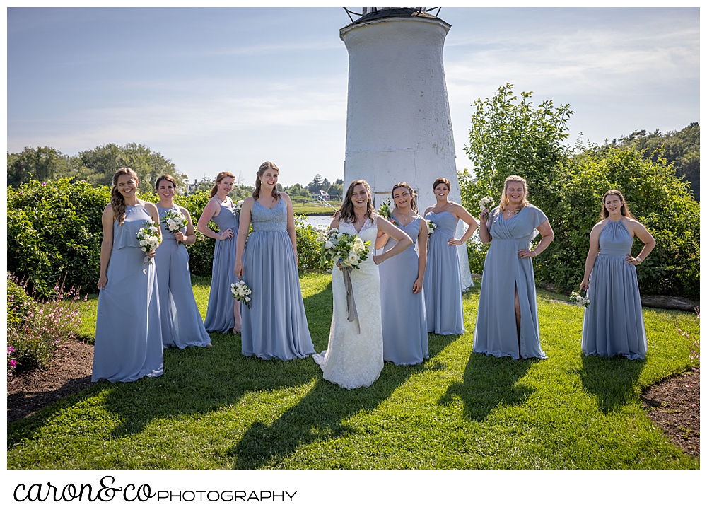 a bride and her bridesmaids stand in a line in front of the lighthouse at the Nonantum Resort, Kennebunkport, Maine