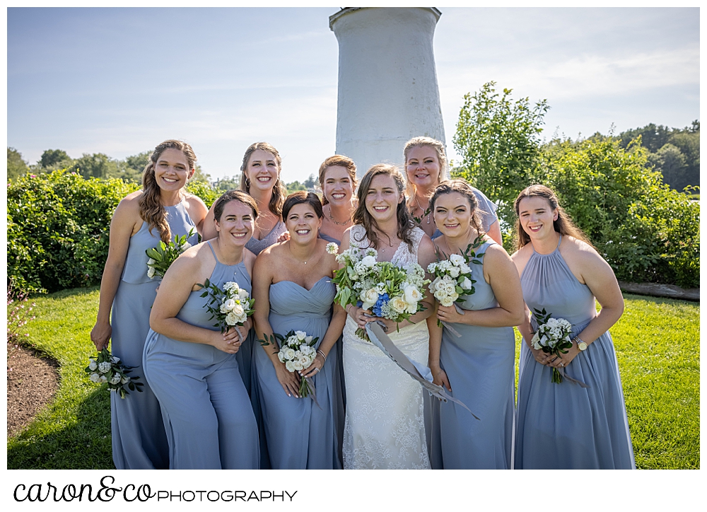a smiling bride is surrounded by her bridesmaids in front of the lighthouse at the Nonantum Resort, Kennebunkport, Maine