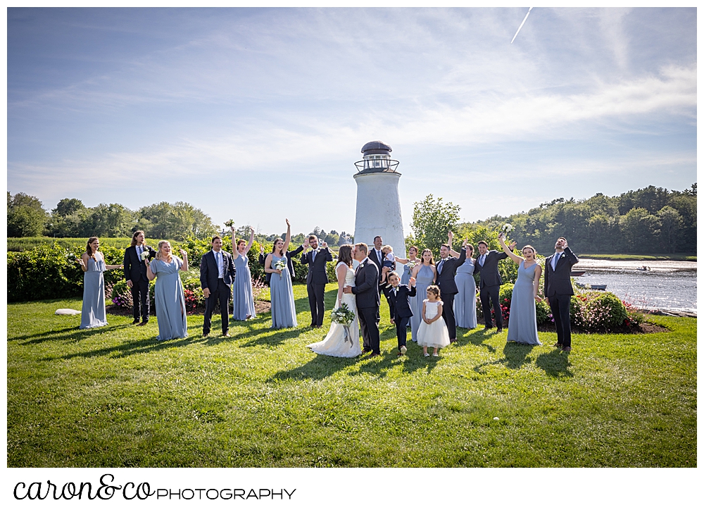 bride, groom, and bridal party standing together on the lawn of the Nonantum Resort, the bridal party is cheering while the bride and groom kiss during their Nonantum Resort wedding celebration