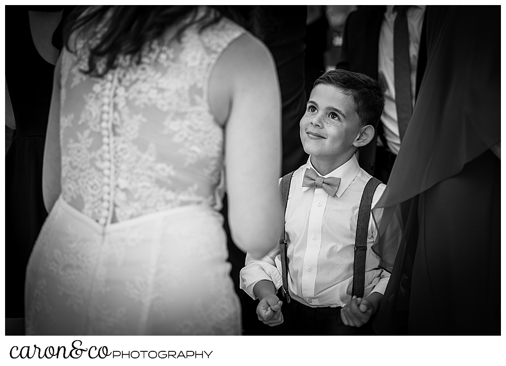 black and white photo of a boy looking up at a bride, the bride's back is to the camera