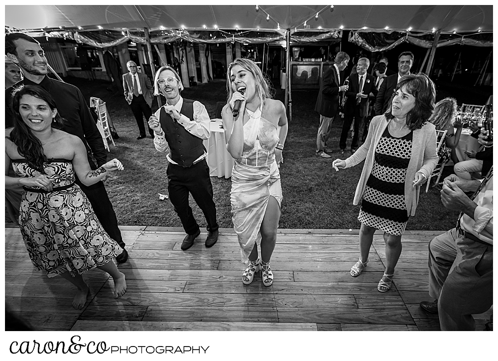 black and white photo of a member of the band Cover Story Entertainment, singing on the dance floor among wedding guests at a Nonantum Resort wedding celebration