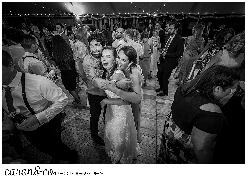 black and white photo of a bride and her friends hugging in the middle of the dance floor during a Nonantum Resort wedding celebration