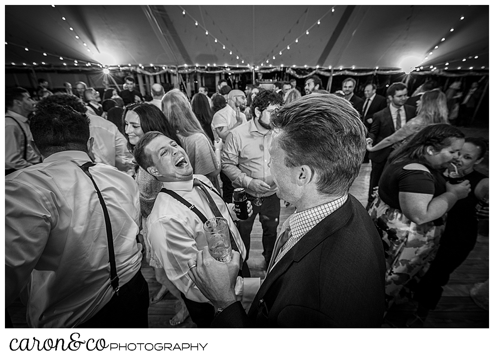 black and white photo of a groom and his friends having fun on the dance floor