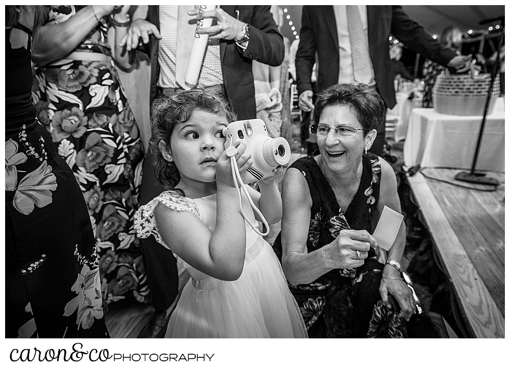 black and white photo of a hound girl with a Polaroid camera up to her eye, while a woman looks on