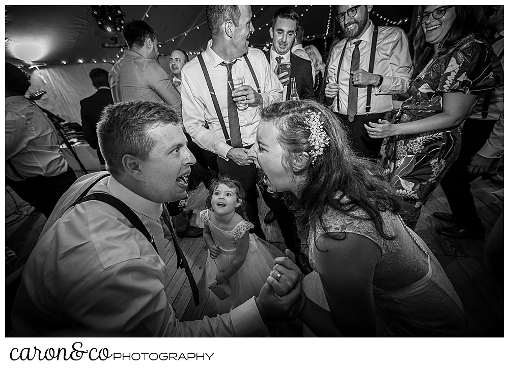 black and white photo of a bride and groom singing to each other, with a young girl watching from the dance floor of their Nonantum Resort wedding celebration