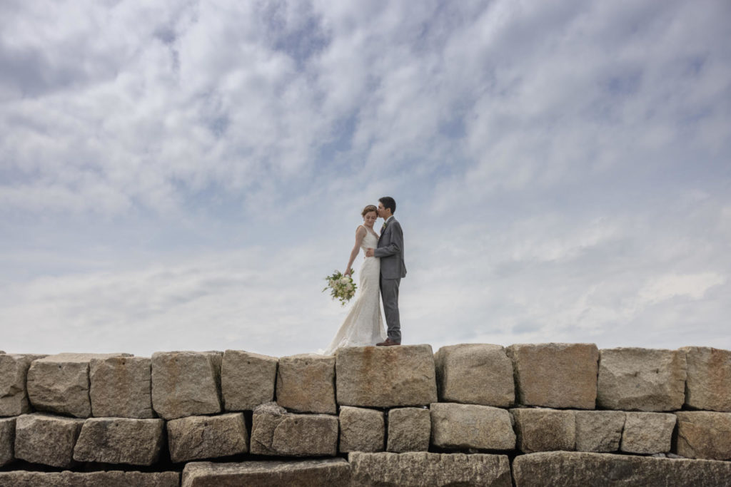 a bride and groom kiss atop the Kennebunkport Maine breakwater