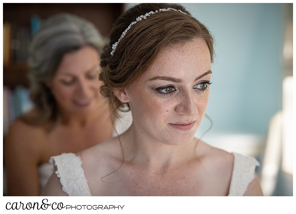 a bride gets ready, with her mother standing behind, helping with her dress